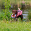 Dog wearing a pink sharki life jacket with a life buoy in its mouth coming out of the water