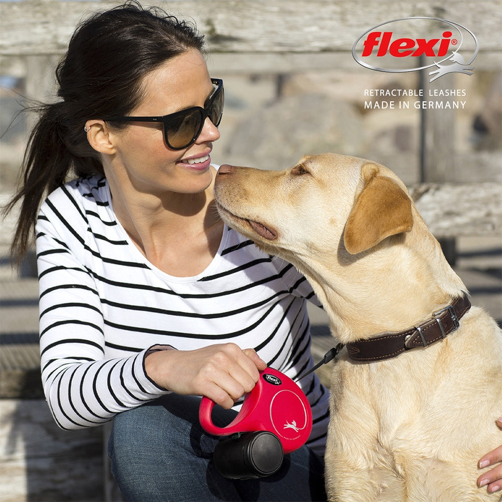 Woman with sunglasses holding a red flexi retractable leash, interacting with a dog.