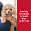 Small dog being held by a person with text about pet food formulation for small dogs up to 11 kg on a red background.