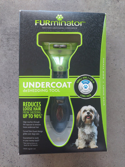 Box of a dog grooming tool with a dog on the label against a gray background