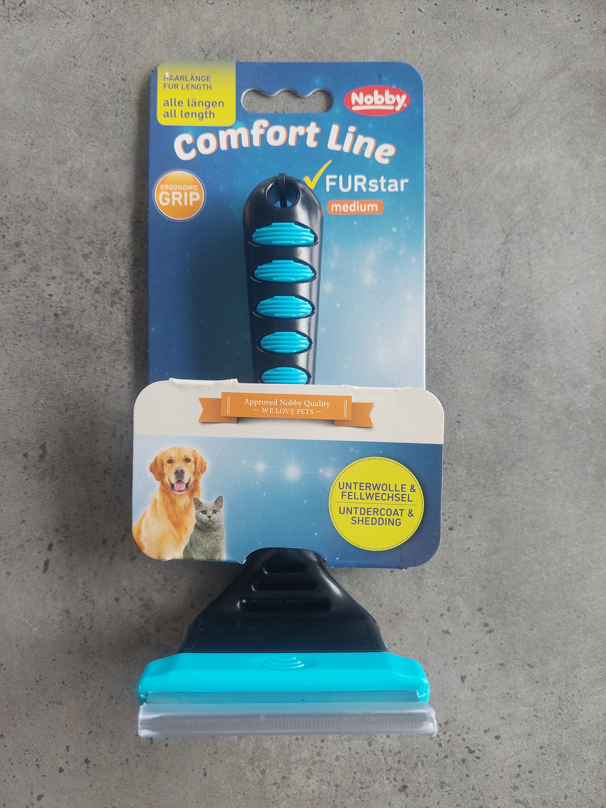 Pet grooming brush with Nobby packaging on a gray surface