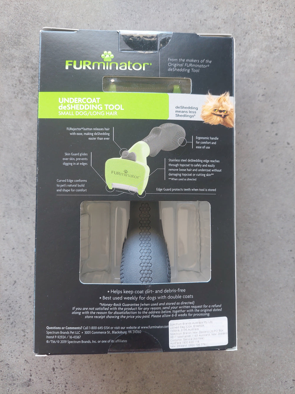 Box of a dog grooming tool with a dog on the label against a gray background